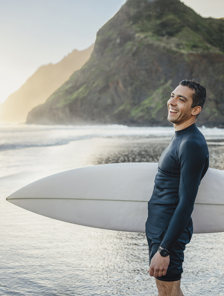 a person in a wet suit carrying a surf board